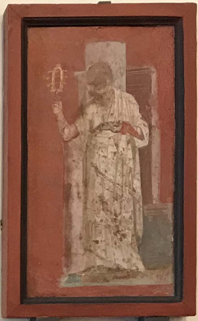 VIII.7.28 Pompeii. April 2019. Painted panel from south portico.
A priestess, with hair gathered behind the head, is shaking a sistrum.
This is the only painting of a woman in the eight paintings of priests from the walls of the portico.
Now in Naples Archaeological Museum. Inventory number 8923.
Photo courtesy of Rick Bauer.