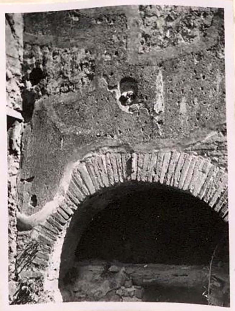 IX.1.3/ IX.1.33. Pre-1943. Brickwork and decorative plaque above oven. Photo by Tatiana Warscher.
According to Warscher –
“Above the opening of the oven, above the brickwork with the phallus, a terracotta head was embedded. 
If I am not mistaken, no-one has mentioned this.  
A. Mau cited a similar head on the hearth of the house at I.3.8, found in 1870.
Unfortunately, the head seen by Mau has gone.” 
See Warscher, T. Codex Topographicus Pompeianus, IX.1. (1943), Swedish Institute, Rome. (no.12a), p. 23.