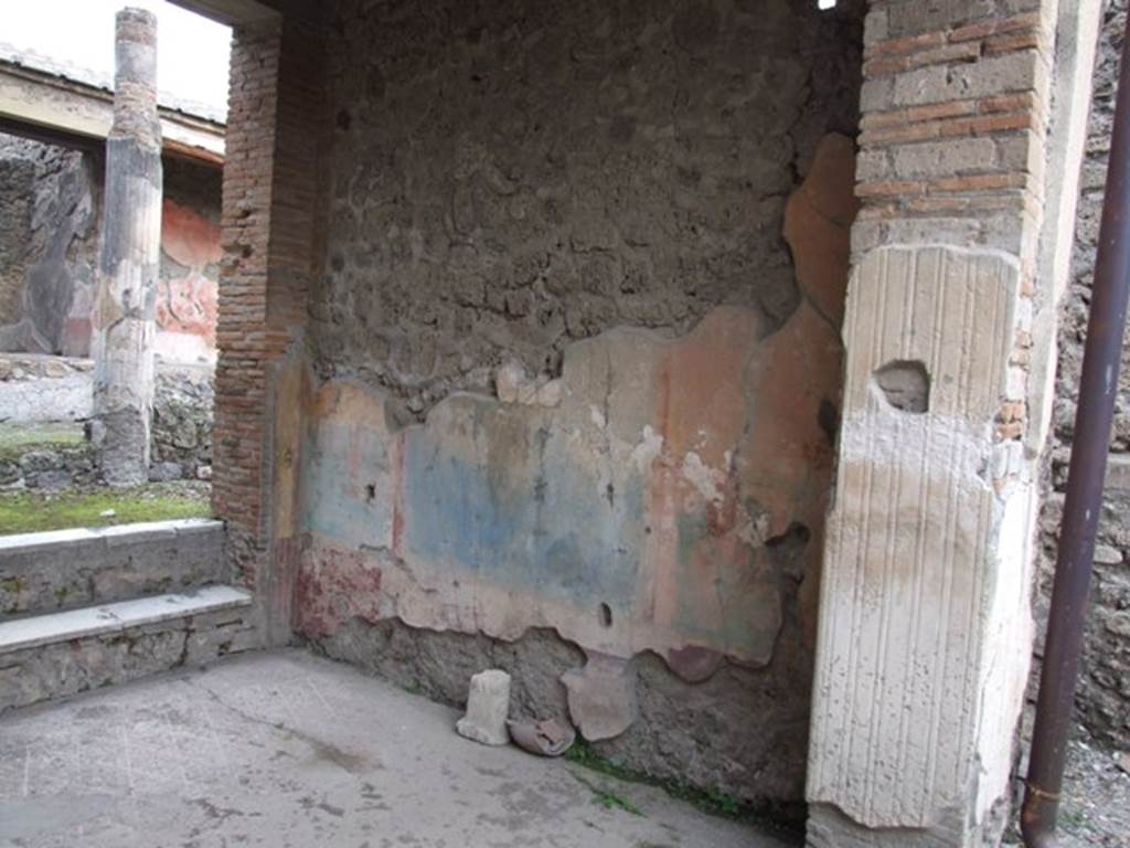 IX.1.22 Pompeii. December 2007. Room 7, east wall of tablinum.  The walls of the tablinum were divided into sections, the centre of the dado (of the east wall) was painted white and dolphins were painted in two small panels, the side panels of the dado were painted purple.
In centre of the middle zone was a blue panel, with a red drape or curtain at the top.
Above the curtain was a naked figure in the centre. In the side panels on a yellow background were architectural paintings. The upper zone was yellow.
See Bragantini, de Vos, Badoni, 1986. Pitture e Pavimenti di Pompei, Parte 3. Rome: ICCD. (p.401, tablino ‘h’)