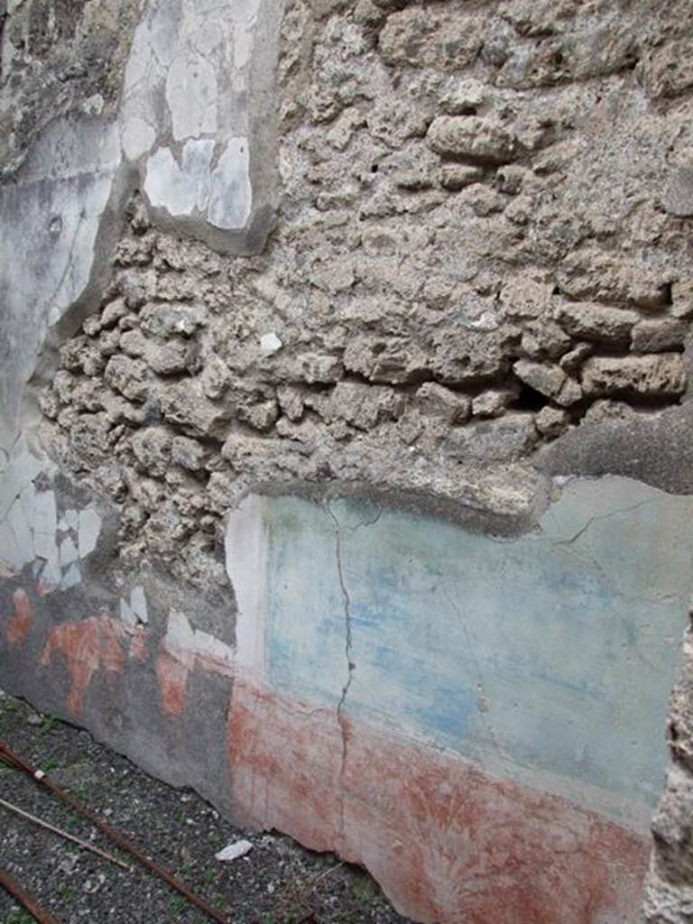 IX.1.22 Pompeii. December 2007. Room 9, remains of painted plaster.  According to Bragantini, the dado in this room was red and painted with plants separated by narrow divisions. The middle zone was painted with blue panels edged with borders with triangles, separated by narrow divisions. Some fragments were put back in situ, after the 1943 bombing.
See Bragantini, de Vos, Badoni, 1986. Pitture e Pavimenti di Pompei, Parte 3. Rome: ICCD. (p.400, cubicolo ‘c’)