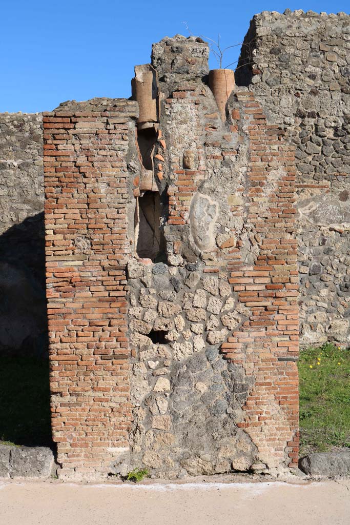 IX.2.2, on left, and IX.2.3, on right. December 2018. 
Central pilaster with downpipe. In the centre of the pilaster is a small terracotta face.
Photo courtesy of Aude Durand.