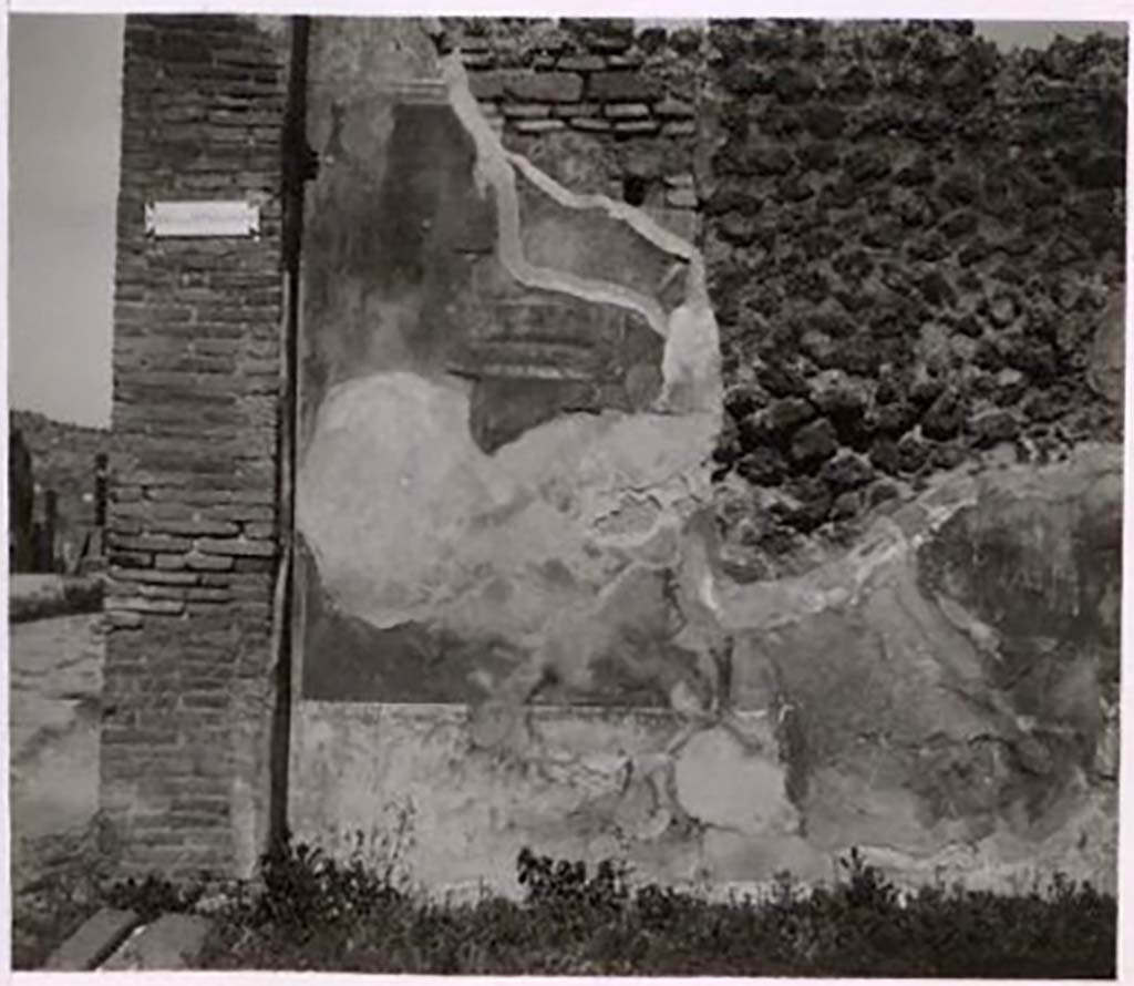 IX.2.7 Pompeii. Pre-1943. 
Looking towards north wall of shop with faded wall decoration. Photo by Tatiana Warscher.
See Warscher, T. Codex Topographicus Pompeianus, IX.2. (1943), Swedish Institute, Rome. (no.17.), p. 42.
According to Minervini -
“The floor of the shop was made from crushed black lapilli.  The walls were painted with several compartments of red, of yellow and of black with various friezes; in the lower part was a black zoccolo with decorations of green plants. On the two side walls were two preserved paintings, and two nearly entirely faded: in one to the left was a swan, in the other to the right was a bird, preparing to peck at some fruit. In the same wall was a small lararium. A white wall continued above the described compartments, with bands of different colors, and with suspended branches. In one of the paintings formed by those bands a vase was seen, and nearby a small thysus; in another a swan, and various decorations, including two candelabras with globes above. Higher up appeared traces of another wall, with paintings of foliage; but not observing traces of support beams, it was very likely that this was an all-wooden construction, which formed a mezzanine, to which one ascended on a wooden ladder.”  
See Bullettino Archeologico Napoletano Nuova Serie: Anno Primo, no.4, Agosto 1852, p.25. Minervini.
