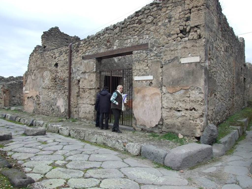 IX.3.19 Pompeii. December 2007. Entrance doorway. According to Fiorelli, “the shop communicated with a bakery, whose doorway was in the eastern roadway (IX.3.20).
It seemed to have been used for the sale of bread, and next to the entrance threshold of the doorway, was a shallow masonry parapet/podium for the mortar, on the other side were the marks for the staircase to the upper floor, under which was installed a storeroom/cupboard with three tiers of shelves. There were two tricliniums lit by windows, the first of which was decorated with two figures of Baccantes, one with thyrsus in hand and a basket on the head, the other carrying a thyrsus in the right hand and a vase in a basket in the left hand. There was also a head of Diana, facing forward, with quiver on the shoulder. A corridor that led to the bakery, had at its extremity the entrance doorway to an oecus/triclinium furnished by two windows, the one facing south towards another triclinium, the other looking out onto the adjacent bakery. The oecus/triclinium was decorated by two paintings alluding to the industry of the place. The first of these showed Ceres, sitting majestically enthroned, behind which was a standing Proserpina carrying a box, and to the right Triptolemus mounting onto the cart pulled by two serpents, scattering the grain on the ground received from the god; whilst the Earth, seen from the back, sitting between two small Genii, clutching the horn of plenty. The second painting showed Ariadne, laying by the sea on a bed of leaves with her head resting on a pillow, found by Bacchus who approached her led by a young Faun, followed by two Bacchantes, and two others that looked on from the top of a cliff.”
See Pappalardo, U., 2001. La Descrizione di Pompei per Giuseppe Fiorelli (1875). Napoli: Massa Editore. (p.147)
and Fiorelli, G., (1875). Descrizione di Pompei, (p.397-8)