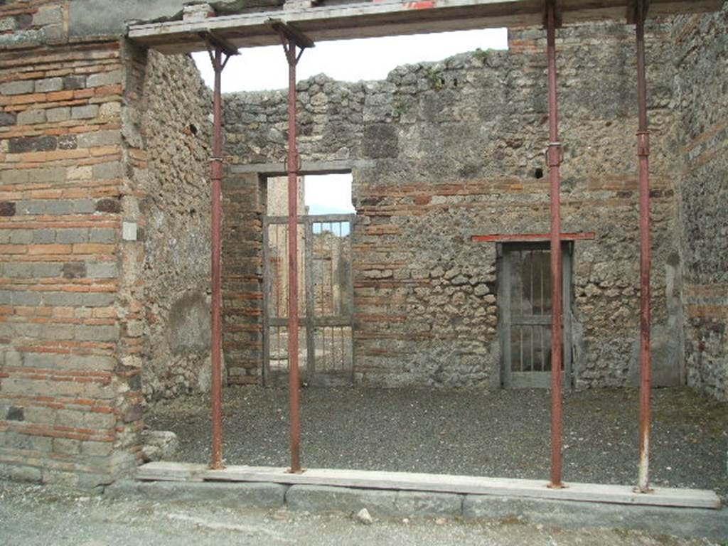 IX.5.1 Pompeii. May 2005. Entrance to shop, with two doorways in the rear wall. One doorway leading to the atrium of IX.5.2, and the doorway on the right, to a rear room (? cubiculum).