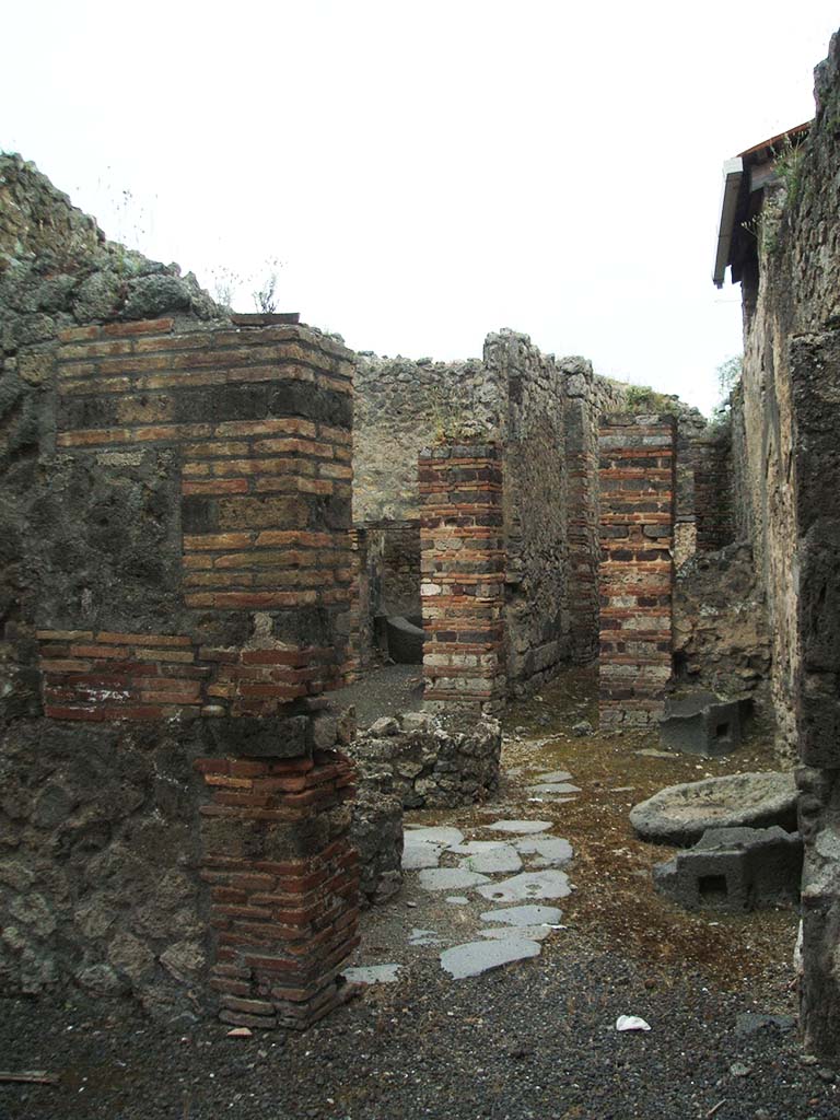IX.5.4 Pompeii. December 2007. 
Looking south into bakery mills area through doorway in south wall of shop-room.