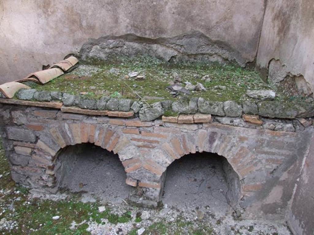 IX.5.6 Pompeii. December 2007. Room p, hearth/bench in kitchen, looking east.  
According to Giacobello, traces of a not very legible fresco found on the north wall of the kitchen near the bench were interpreted as a lararium. 
This was at the time of excavation.  See Mau in BdI 1879, p.116.
See Giacobello, F., 2008. Larari Pompeiani: Iconografia e culto dei Lari in ambito domestico. Milano: LED Edizioni, (p.285).