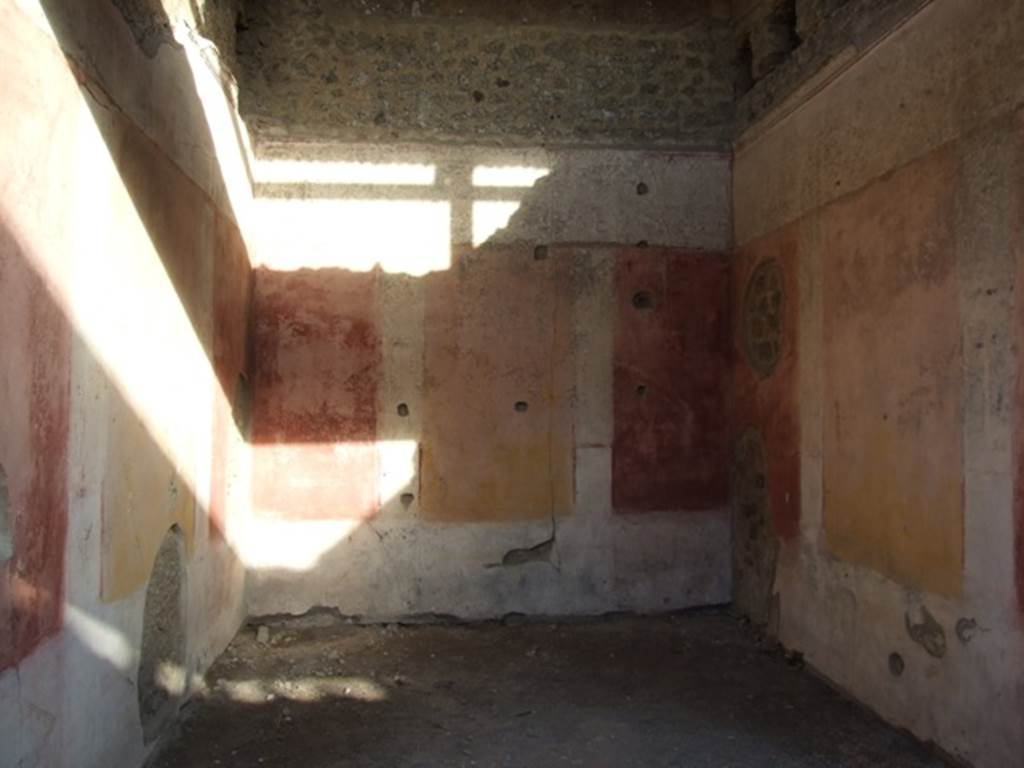 IX.5.11 Pompeii. December 2007. Room 3, looking east. The ala was decorated with red and yellow panels, in half of which were painted Cupids. Under the panels was a black zoccolo, and above them was a frieze finishing above with a stucco cornice. In the small panels of this frieze we see painted on the back (east) wall, a woman’s figure on foot, crowned with fronds and dressed in a green robe, holding a plate or basket in her left hand, and holding the lower edge of her robe with her right hand. On the wall to the right, was a Cupid with club, and under in small rectangles with purple backgrounds, one sees two fighters with daggers. On the wall to the left, finally we have another Cupid, that has in his right hand a bunch of grapes and in the left, an object that cannot be defined, below in a rectangle with purple background, one sees an open volume, on which were painted some black words, in part vanished and difficult to read. 
See Notizie degli Scavi, 1877, p.248
