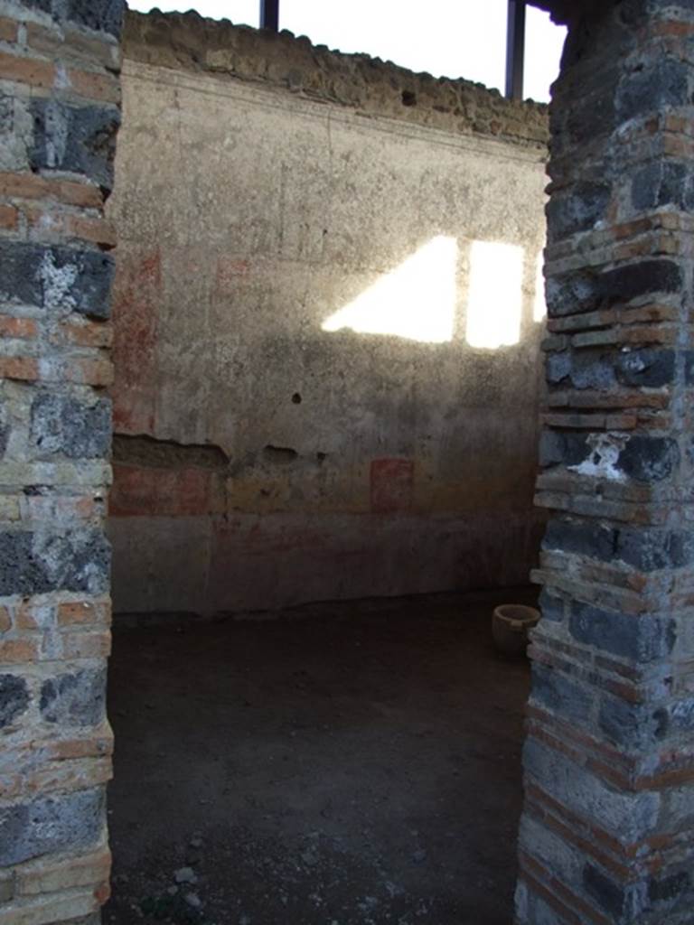 IX.5.11 Pompeii. December 2007. Doorway to room 4, looking east. This room also had a decoration of red and yellow panels, fragmented by ornate architecture. In the yellow panels were small paintings. The one on the north wall (0.51 x 0.44) showed a naked standing Bacchus, crowned with foliage, leaning on a pilaster with his left elbow, inside his elbow was his cloak. In his right hand was a short rod/staff, near to him on the ground was an amphora with a wide neck. Of the other two paintings on the east wall, the first (0.45 x 0.53) showed a Cupid, with two whips, one in each hand following a goat. The second (0.45 x 0.42) also showed a Cupid encouraging a dog to attack a rabbit. The west wall having been holed did not preserve any paintings in its panels. 
Whereas on the south, under the window, the yellow plaster that one sees above a most antique decoration (II Style) was decayed. White lozenges (diamonds) were in the red panels, in each lozenge was a painted Cupid, some with rod and pan-pipe, some with crook or with a cornucopia. In the panel of the frieze, finishing above of an elegant cornice of stucco, were painted some isolated figures, around 0.54 high. 
Beginning from the north wall, one had -
1.)  Female standing woman, with long purple robe.
2.)  Satyr crowned with reed, with greenish cloak, having a torch in his right hand and a bunch of grapes in his left hand. 
3.)  Female figure with green robe, with left hand raised to her head and holding the edge of her cloak.
4.)  Female figure with purple robe, with a garland of leaves between her hands.
5.)  Naked Satyr, with cloak around his legs, the shepherd’s crook in his left hand, and pan-pipe in his right.
6.)  Female figure dressed in dark green robe with a yellow tunic above, holding a lance in the left hand.
7.)  Another female figure with red robe and yellowish cloak, who had a fan in the guise of a leaf in her right hand.
8.)  Virile naked figure, except for a purple cloak that fell from his shoulders and which was wrapped around his left arm, in his right hand he held an  arrow tied to a snare, whose other end he held in his left hand.
9.)  Virile figure, badly preserved, with dark green cloak and a lance.
10.) Woman with green robe, gazing intently into a round mirror held in her left hand: the mirror did not have a long handle, but was held on the wrong  side.
11.) Another woman with a yellow robe and greenish cloak, who held a basket filled with fruit in both hands.
See Notizie degli Scavi, 1877, (p.248-9)
See BdI, 1879, (p.198-201)