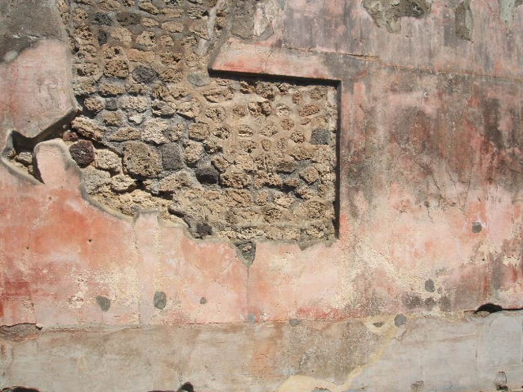 IX.5.14 Pompeii. May 2005. Room “f”, north wall of triclinium with painting cut from it.
In the black zoccolo were panels with squares alternating with narrow compartments with painted plants: 
Seen in the side panels of the red middle zone of the wall, were vignettes with painted Muses, (but badly preserved). 
In the centre would have been a painting with a scene of uncertain identification, possibly Dido receiving Aeneas for the first time.