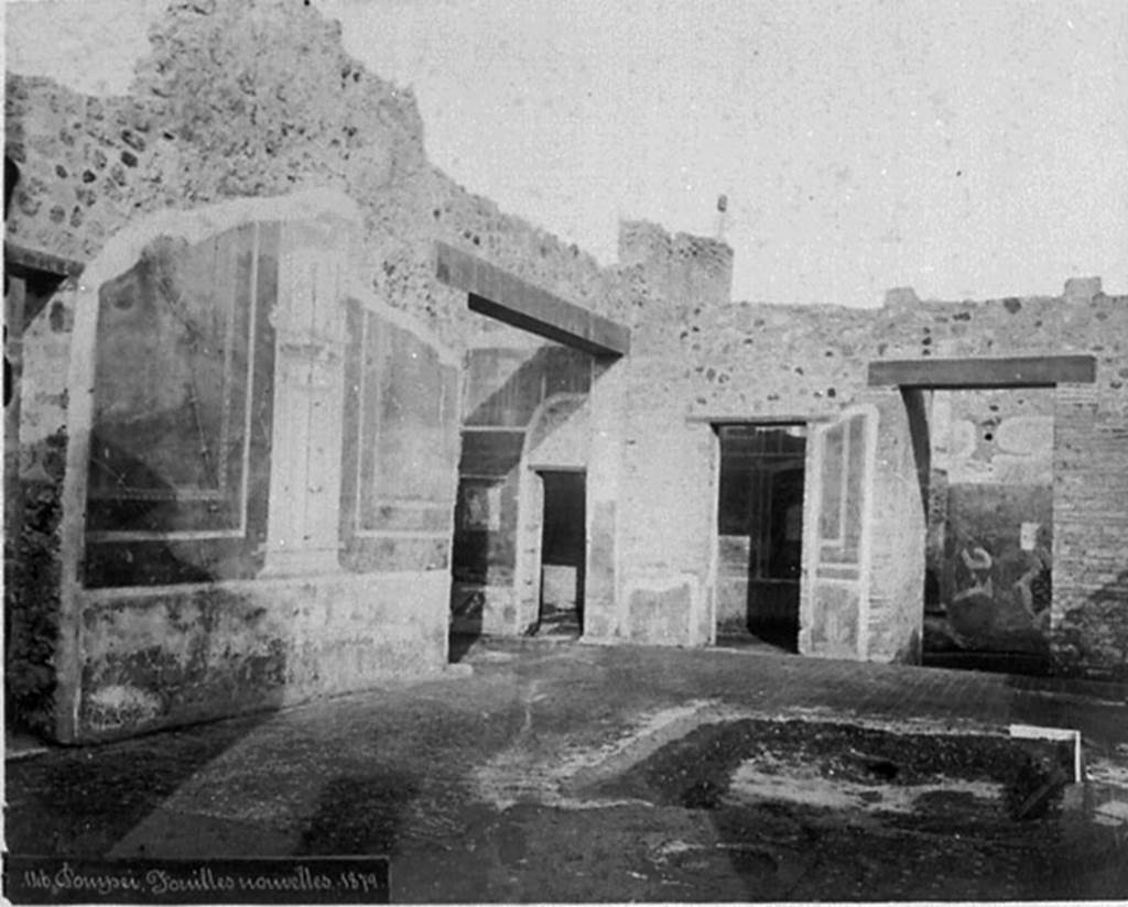 IX.5.14 Pompeii. Old photograph, c.1880.
Looking north-east across atrium, with remains of the impluvium in the floor of cocciopesto dotted with small crosses of white tesserae, with black centre.
Room “e” an ala, with doorway to room “d”, can be seen in the centre, then to its left – the doorway to room “c”, and entrance corridor “a”, on the right.