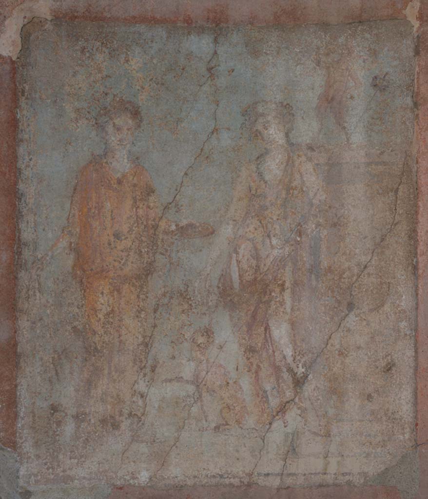 IX.5.14 Pompeii. May 2017. 
Room “g”, central wall painting from east wall of Ariadne and Dionysus with panther and a statue of Pan.
Foto Christian Beck, ERC Grant 681269 DÉCOR.
Kuivalainen’s description is of –
“A composition of two persons, a panther and a statue, outdoors on green terrain with a light blue background.
On the left, a female wearing a yellow/orange tunic stands almost frontally with her weight on her left foot; she has a wreath of ivy on her head; in her right hand she holds a thyrsus, with her left she holds out a patera towards the youth in the middle. He stands with his weight on his right foot, wearing long boots, a pardalis, and a long violet cloak on his left arm; he has a wreath of ivy in his curly hair; in the bend of his left elbow he holds a thyrsus with a small bunch of leaves on top; in his right hand he holds a cantharus, out of which he pours wine into the mouth of a sitting panther with its right foreleg raised. On the right there is a pedestal, the front side of which is decorated with patera, on top of which stands a small dancing faun with hairy legs and hoofs; his right arm is outstretched, and in his left he holds a pedum.”
Kuivalainen comments –
“It is more likely that young Bacchus is depicted in the company of Ariadne rather than Libera, due to the colour of her dress perhaps a reference to flammeum”. (405).
(Note 405 reads – A flame coloured veil worn by Roman brides, e.g. Plin. nat. 21.46.)
See Kuivalainen, I., 2021. The Portrayal of Pompeian Bacchus. Commentationes Humanarum Litterarum 140. Helsinki: Finnish Society of Sciences and Letters, (p.127-8, D5).