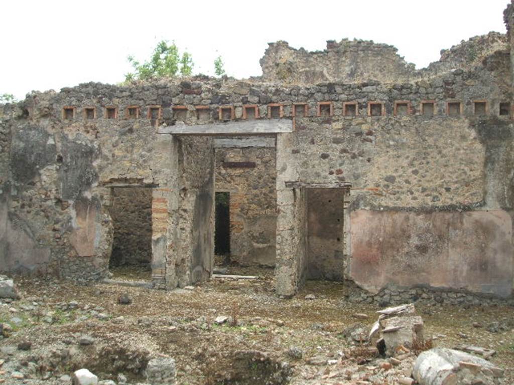 IX.5.18 Pompeii. May 2005. Looking south across atrium, room b, towards the entrance doorway, in centre. The doorway on the left leads into room h, which according to Zevi measured approximately 3.50m x 3.70m. It was the kitchen area with a latrine and masonry hearth. The walls were roughly plastered but on the left  (east) wall was a simple decoration consisting of a yellow zoccolo, and red upper face to the walls.
See Zevi, F., 1964.  La Casa Reg IX.5.18-21 a Pompei e le sue pitture: Studi Miscellanei 5.  Roma: Bretschneider. (p.9 and note 22)