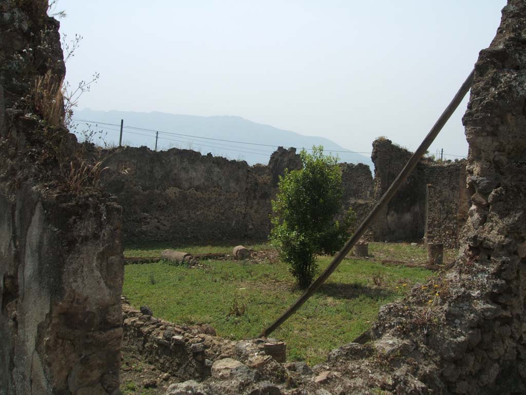 IX.6.7 Pompeii. May 2005. Looking south-west through doorway to east end of peristyle “3” of IX.6.5.
The wall (pluteus), that joined the columns on the east side of the peristyle, can be seen in the lower middle of the photo.