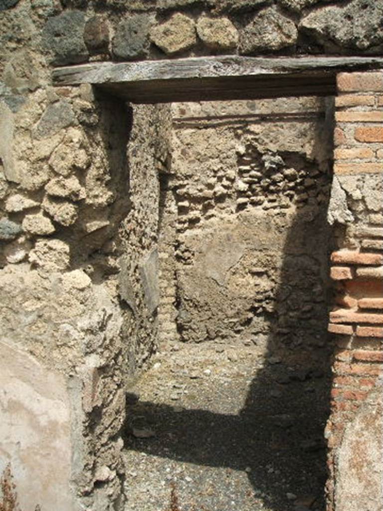 IX.6.a linked to IX.6.1 Pompeii. May 2005. Doorway to rear on north-west side of shop, with doorway to IX.6.1. Left of centre, on the west wall, the line of the site of the stairs can be seen in the plaster remains. According to Flohr, this room contained the stairs to the upper floor, which extended above all three ground-floor rooms. See Rivista di Studi, XVIII, 2007, article by Flohr, M, entitled Cleaning the laundries report of the 2006 season, (p.134).