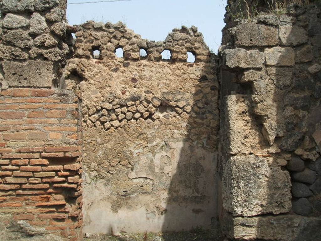 IX.6.a Pompeii. May 2005. Doorway to rear room on north-east side of shop, with holes for beam supports for upper floor, and remains of white plastered walls.