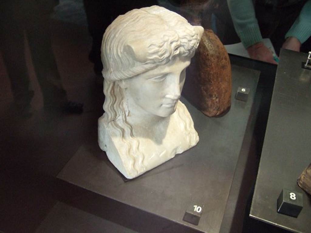 Marble statuette of Iside-Io? Found in IX.7.23, according to Naples Museum card.  
Now in Naples Archaeological Museum.  Inventory number 119584.
According to Jashemski and Dwyer, this was found in the atrium of IX.7.20, but probably belonged to the peristyle.
It was discovered on 28th October 1880, and described as –
Bust for a herm. White marble. Height m.0.21.
The back of the bust is flat and the sides show cuttings for cross-bars.
A river god, with bull’s horns protruding from above temples.
Hair parted down the middle, descends in wavy tresses to chest.
See Jashemski, W. F., 1993. The Gardens of Pompeii, Volume II: Appendices. New York: Caratzas. (p.241)
See Dwyer E., 1982. Pompeian Domestic Sculpture, Rome: Bretschneider, pp.71-78.