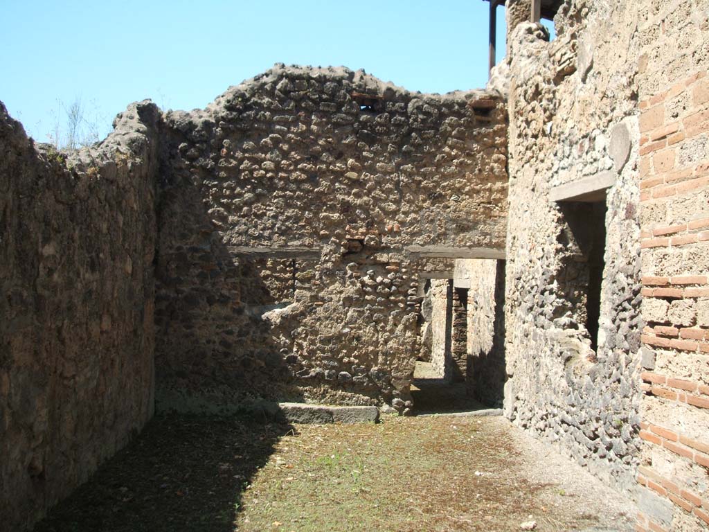 IX.7.20 Pompeii. May 2005. Looking west across garden area (room u) towards corridor to services area (room v).
According to Jashemski, Mau thought this large L-shaped area on the south side of the house was a garden or courtyard.
The triclinium on the north (room “s” on the right of photo) had a window onto the garden which gave it light.
See Jashemski, W. F., 1993. The Gardens of Pompeii, Volume II: Appendices. New York: Caratzas. (p.242)
