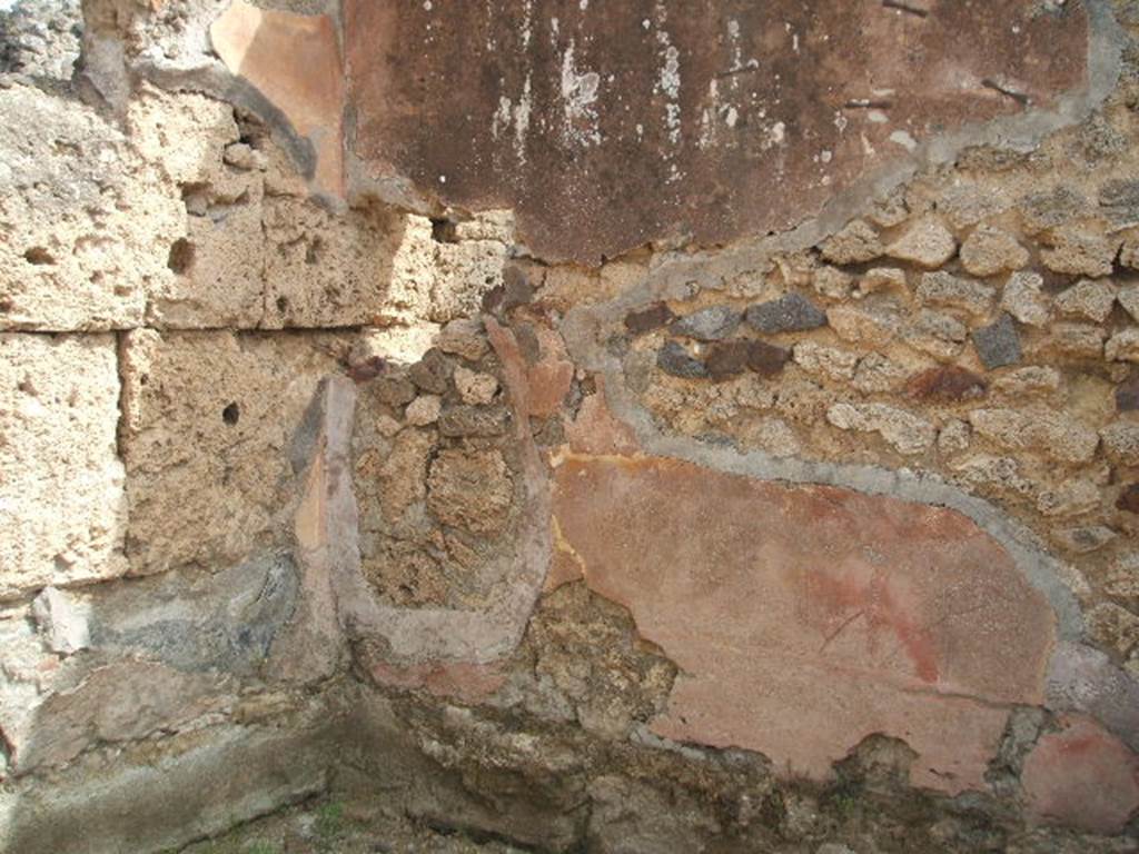 IX.7.21/22 Pompeii. May 2005. Remains of painted plaster in north-east corner of the room on east side of caupona. According to Mau, this room was the only one that had well conserved plaster. It was painted simply and clumsily in the last IV style, and on a yellow background.
In the middle of each of the divisions on the walls, there were similar square paintings representing a bird pecking at fruit, on a yellow background. See Mau in BdI, 1882, (p.194)
According to PPP, the north wall had a red lower area. The east wall had the lower portion of the walls painted red, in the middle area were narrow red central divisions with yellow panels, the upper area was painted red. The south wall had the lower portion painted red, the middle section painted yellow with panels. See Bragantini, de Vos, Badoni, 1986. Pitture e Pavimenti di Pompei, Parte 3. Rome: ICCD. (p.507)