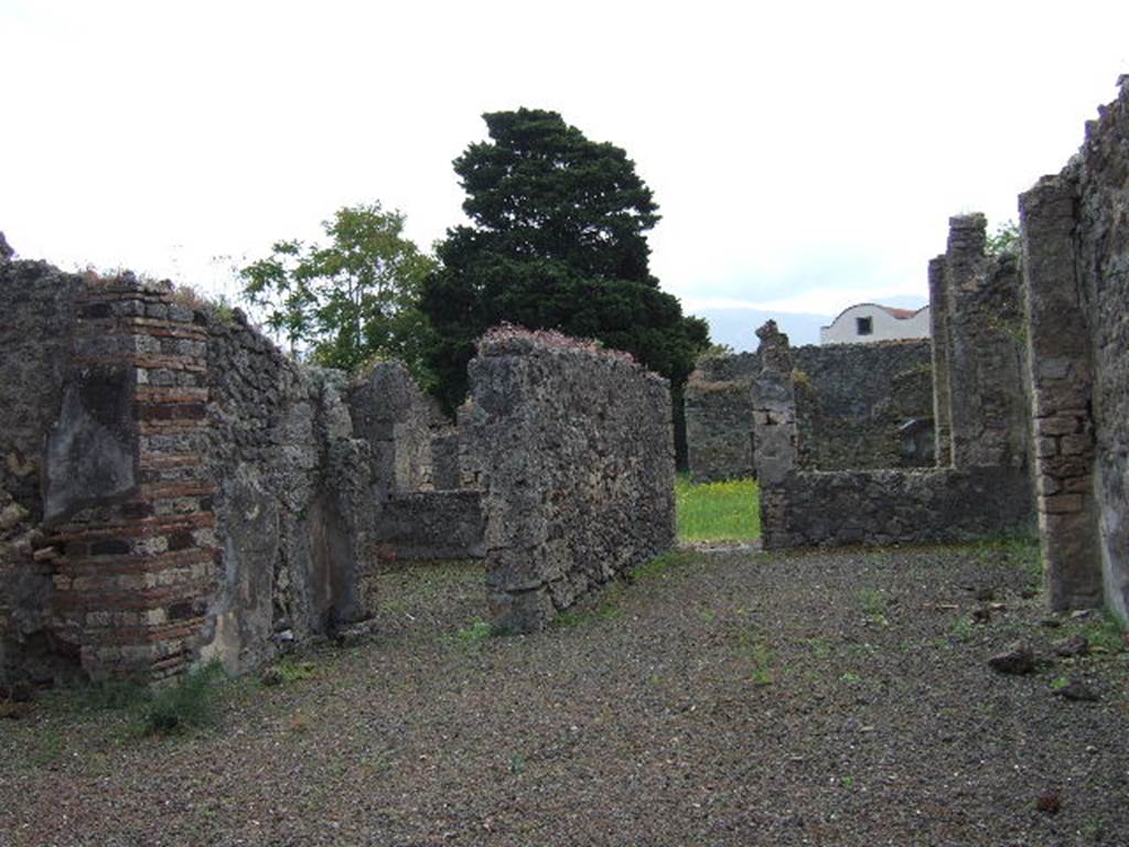 IX.9.4 Pompeii. May 2006. 
Looking south across atrium, with doorway to room ‘g’, triclinium, left of centre, and doorway from room ‘f’, tablinum to garden.
According to Boyce –
In the north wall of the portico which looks out onto the garden from the north side, is a vaulted niche (h.0.40, w.0.40, d.0.12, h. above floor 1.60) – probably the lararium, according to Mau. On the ground before it lies a cube of travertine (0.24) which may have served as altar.
See Boyce G. K., 1937. Corpus of the Lararia of Pompeii. Rome: MAAR 14. (p.91, no.455). 
See Giacobello, F., 2008. Larari Pompeiani: Iconografia e culto dei Lari in ambito domestico. Milano: LED Edizioni, (p.286 no.V82)