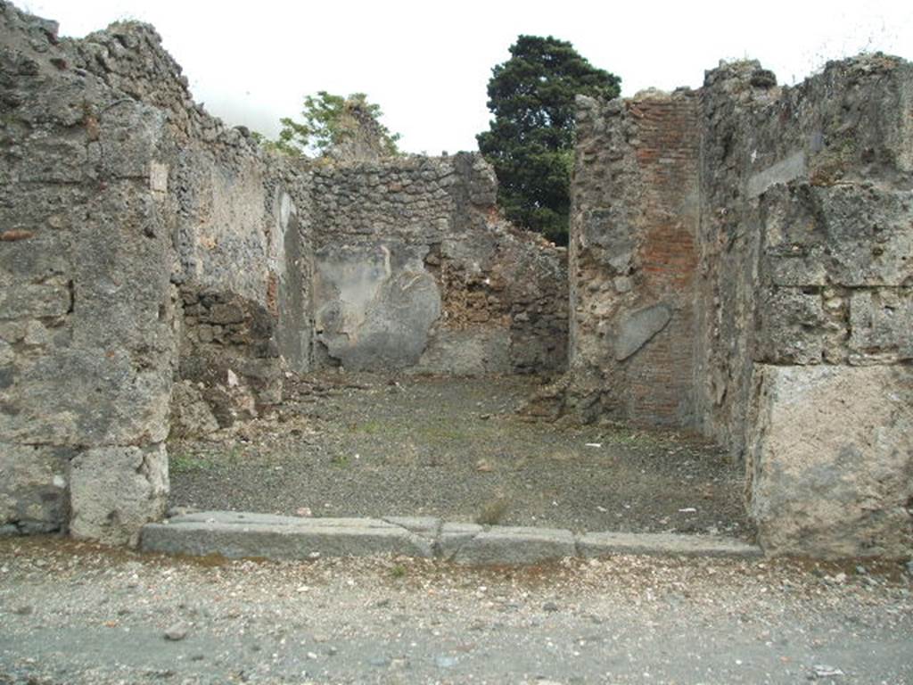 IX.9.7 Pompeii. May 2005. Entrance doorway, looking south towards rear room. According to NdS, this shop communicated with the entrance corridor of the adjacent house (on the right). The rear room had walls with white decoration, and a window which was found destroyed in the pilaster to the right of the entrance room. On this pilaster, in the front shop-room, a series of vertical and parallel lines traced with charcoal were found, which were undoubtedly accounts. It was likely that here in this shop, the vinarius (vintner) owner or tenant of the adjacent house, sold his wines, and in fact, five amphorae were found (see NdS, 1888, p.523)
See Notizie degli Scavi, 1889, p.126.