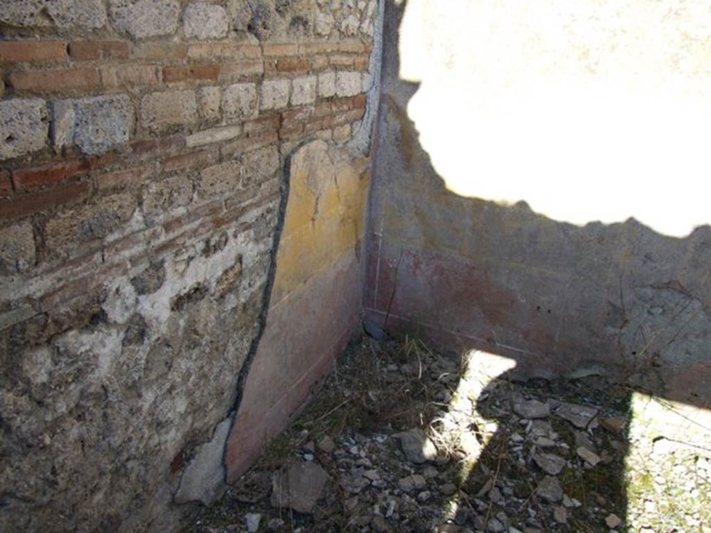 IX.9.a Pompeii. March 2009. North-east corner of cubiculum “i”.  This bedroom was described as having flooring of crushed brick (mattone pesto) and with pieces of coloured marble of various forms and sizes added to it. The walls were plastered, with a yellow background in the middle part, with a white frieze and red plinth or dado. In the middle of the yellow panels were rather crudely painted doves. See Notizie degli Scavi, 1888, p.515.