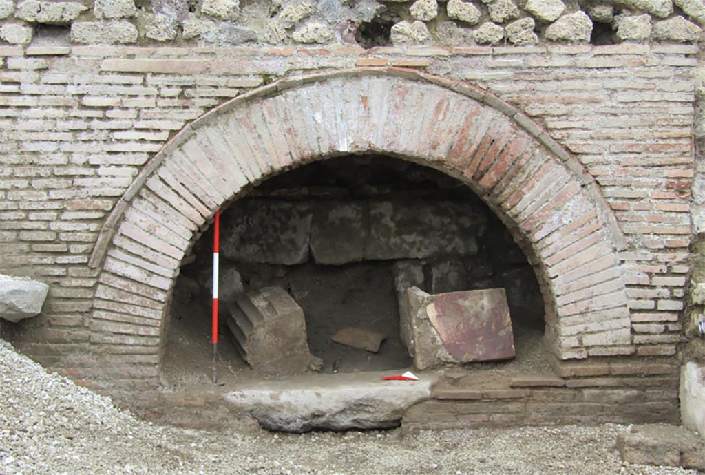 IX.10.1 Pompeii. December 2023. Oven 7a. Looking west to the oven front. 
The partially visible structures already suggested the presence of a production facility with an oven, a hypothesis that was confirmed when the burying material was removed. 
Along the north wall of oven 7a, a rectangular basin (ca. 1.50 x 0.80 m) was uncovered, the bottom of which has not yet been reached.
A significant feature of room 7 is the presence of two circular masonry structures, not entirely visible at present, on which the circular cones of two millstones must originally have rested, cones that are, however, not present on the bases. The condition of the excavation, which is still in progress, leads one to be cautious; however, it is legitimate to ask whether the absence of the millstones is attributable to removals that occurred during the 19th-century excavations.
IX.10.1 Pompei. Maggio 2023. Forno 7a. Vista verso ovest sul fronte del forno. 
Le strutture parzialmente a vista facevano già supporre la presenza di un impianto produttivo con forno, ipotesi che ha trovato conferma allorché si è proceduto alla rimozione dell’interro.
Lungo la parete nord del vano 7a si è messa in luce una vasca rettangolare (1.50 x 0.80 m ca.) di cui ancora non si è raggiunto il fondo.
Elemento significativo di ambiente 7 è la presenza di due strutture circolari in muratura, attualmente non del tutto visibili, su cui, in origine, dovevano poggiare le mete circolari di due macine, mete che però non sono presenti sulle basi. La condizione dello scavo ancora in fieri induce ad essere cauti, ad ogni modo è lecito domandarsi se la mancanza delle macine sia imputabile ad asportazioni avvenute durante gli scavi ottocenteschi.
Photograph © Parco Archeologico di Pompei.
Vedi/See Ri-scavare Pompei: nuovi dati interdisciplinari dagli ambienti indagate a fine ‘800 di Regio IX, 10.1.4. E-journal 2, Scavi di Pompeii, 29.5.2023, p. 4, fig. 3. E-journal on PAP web site