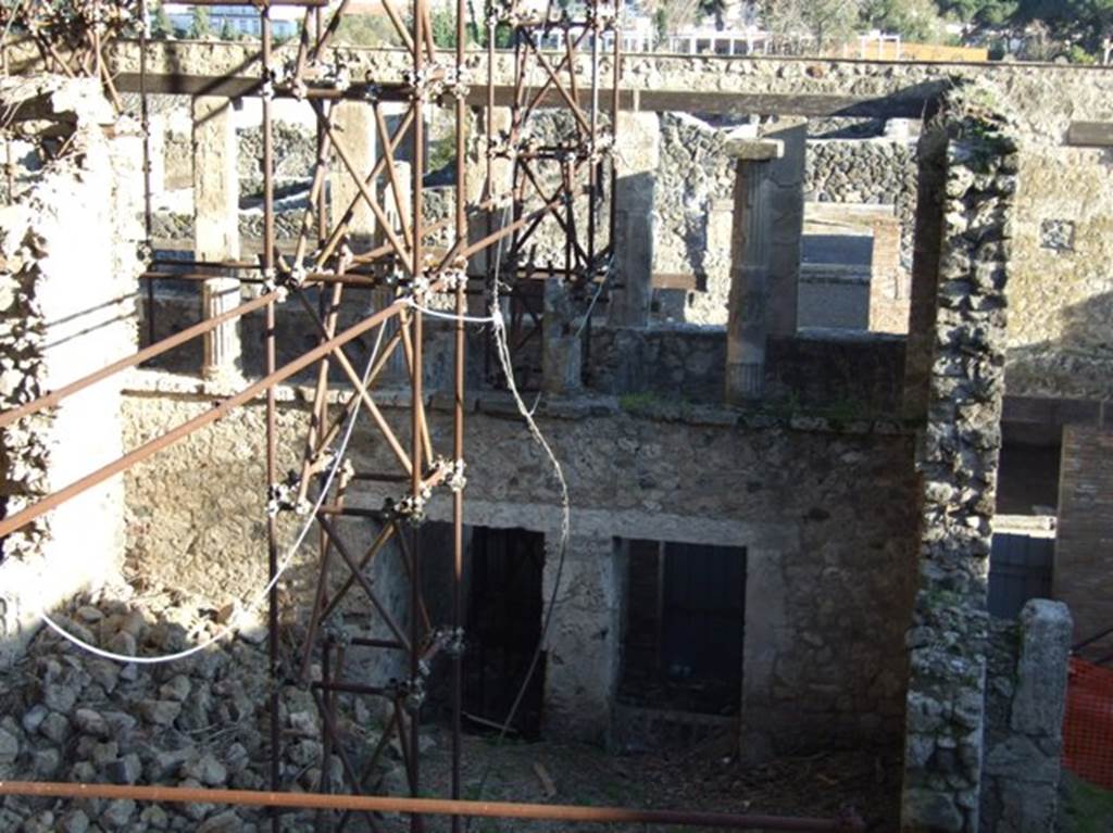 IX.12.4 and IX.12.3 Pompeii. March 2009. Taken from the rear.  
Looking south to rear of upper cenaculum/terrace, and rooms below. The atrium “c” is the lower part of the photo.
When found, the atrium was completely empty of plaster in all its vast space.
The west and east walls were continuous, other than for a doorway in the east wall opening in the north-east corner.
Here was the wooden stairway rising to the upper floor, no less than 6.50m long by a height of 5m, roughly.
In the north wall were two doorways. 
The one on the west side leading to a long and narrow room (not less than 6 x 3m) with a doorway penetrating under the upper rear rooms of IX.12.1, leading west into a short passageway. The one on the east side, another vast rectangular room (6.50 x 3.60m) and at its rear leading to a narrow room (less than 1.50 by around 10.70m), perhaps unroofed and giving light to the room and passageway. 
See Spinazzola, V. Pompei, alla luce degli Scavi Nuovi di Via dell’Abbondanza (Anni 1910-1923), Vol.2, p.715-6.
The door to IX.12.2 (separate steps to an upper floor) is on right.