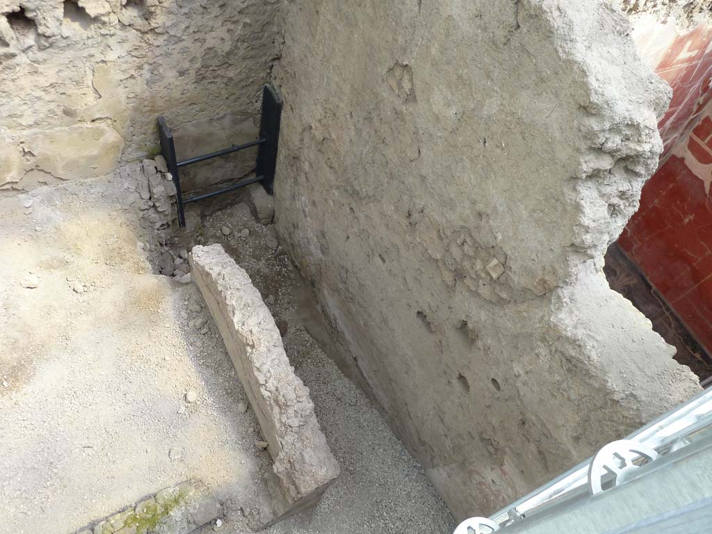 IX.12.B/IX.12.9 Pompeii. May 2010.  
Room “a”, south end. Next to the room where the skeletons were found was a kitchen, with a stone counter on which a pile of lime for building purposes was found, and a long narrow room with a latrine, the contents of which flowed into a drain beneath the street. The backfill directly covers the pavement made up of five tiles with quarter-circle fins, arranged flat The tiles have a gradual slope from the kitchen counter, which occupies the south-west corner, towards the latrine drain on the street.
See PAP: New victims from Pompeii emerge from the excavation of the house of the chaste lovers
Stanza 13, lato sud. Accanto alla stanza in cui sono stati trovati gli scheletri c'era una cucina, con un bancone in muratura sulla sua superficie si trova infatti un mucchio di calce in polveri per la costruzione, e una stanza lunga e stretta con una latrina, il cui contenuto sarebbe defluito in un canale di scolo sotto la strada. Il terreno di riporto copre direttamente il lastricato composto da cinque tegole con aletta a quarto di cerchio, disposte di piatto. Le tegole hanno pendenza digradante dal banco della cucina, che occupa l’angolo sud-ovest, verso lo scolo della latrina sulla strada.
Vedi PAP: Pompei due scheletri rinvenuti sotto un crollo di muro