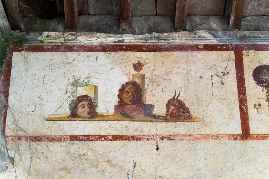 IX.13.3 Pompeii. October 2021. 
Room 9, detail of panel with painting of masks or heads, from north end of east wall. Photo courtesy of Johannes Eber.