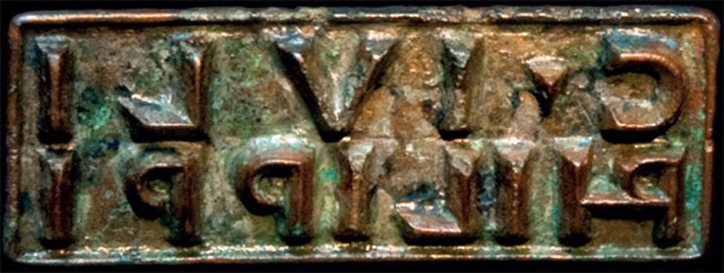 IX.13.1-3 Pompeii. 1973. Bronze seal of C. IULI PHILIPPI (Caius Iulius Philippus) found in chest in Room 9, east portico.
According to Varone, on the 8th February 1973 (7 January according to Giordano), along the eastern ambulatory of the house, wooden cabinets were discovered in one of which, between various precious objects, was found a bronze seal inscribed with C (ai) IVLI PHILIPPI.  The bronze seal is a symbolically individual tool. It was used to mark, as a signature, for example, the veracity of the contents of a message. After engraving with the stylus, the wax tablets were folded one against the other to form a diptych, they were bound by a ribbon closed by sealing wax on which was stamped the seal of person who thus signed for the content. It will be understood, then, like the seal of a modern notary it constituted a personal element to be jealously guarded. It was in fact worn on his finger or kept in a safe. We cannot doubt, then, that Iulius Philippus lived in this house.
Graffiti in the house shows that Philippus and Polybius had a close relationship, which may have been father and son, but it is not clear who is which. However, I think, without wanting to go into a whole series of evaluations, but I think, though it would still be questionable, that it was most likely Philippus was the father of Polybius.
See Varone A., 2015. Indagine su un cittadino al di sopra di ogni sospetto: Giulio Polibio, in Caio Giulio Polibio, 2015. Napoli: IDSN, p. 97-8, p.104.