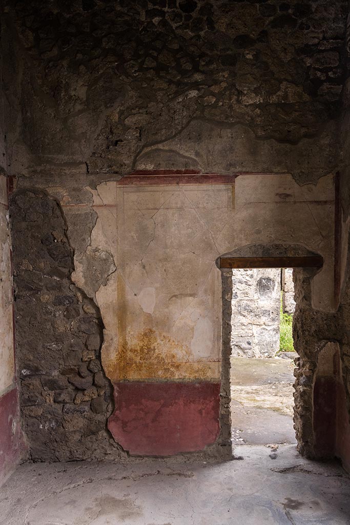 IX.14.4 Pompeii. July 2024. South wall of room F on the east side of the atrium. 
The small doorway in the south wall led into the eastern ala G. Photo courtesy of Johannes Eber.