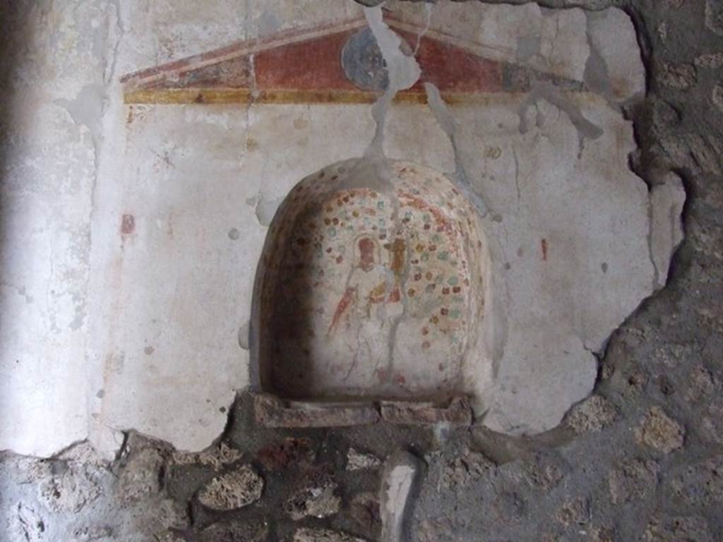 IX.14.4 Pompeii. December 2007. Arched niche set in painted aedicula, on south wall of kitchen 18.
According to Boyce, a rectangular space was enclosed within a simple painted aedicula of slender columns supporting a pediment.
The pediment represents red marble with insets of green in the centre and at each lower corner.
The inside walls of the arched niche are thickly covered with spots of yellow, green and red.
On the rear wall is a figure, which the report in Not.Scavi called Fortuna, but which certainly represents the Genius.
He holds cornucopia in his left hand and a patera in his right. There is no altar.
In the spaces at the sides, and below the niche but still within the painted aedicula were the following painted figures –
On each side of the niche was a Lar. Above each Lar was a garland with a bird perched on it.
Below the level of the niche was, on the right, a hog advancing to the left, and on the left was a banqueting scene with six persons upon a triclinium, three men and three women.
Immediately below the niche was a single serpent gliding right amongst the plants.
Between the entrance doorway to the room ad this Lararium was painted a figure of Hercules with the club upon his shoulder.
The whole painting is very crudely executed.
See Notizie degli Scavi di Antichità, 1911, p. 214, with photo p. 217.
See Boyce G. K., 1937. Corpus of the Lararia of Pompeii. Rome: MAAR 14. (p.31, no.68 & Pl.13, 2) 
See Fröhlich, T., 1991. Lararien und Fassadenbilder in den Vesuvstädten. Mainz: von Zabern. (L111, T. 48,1).