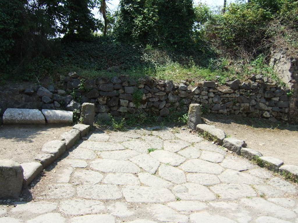 HGW06 Pompeii. May 2006. Entrance, looking west. According to Spano, at the entrance of the villa during a small excavation, two semicircular walled bases were completely disinterred (from 60 to 90cm high). These had the remains of red painted stucco on their exterior.
They were probably used to contain plants decorating the entrance of the villa. Their internal surfaces were coarse and the absence from either of any trace of a water-pipe excluded the idea that these were used as fountains. See Spano in Notizie degli Scavi, 1910, p.268-9.
