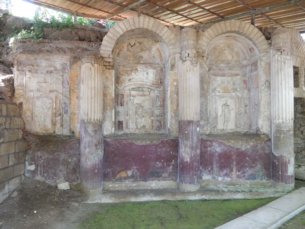Villa San Marco, Stabiae, June 2019. 
Area 65 at southern end of west portico with curving wall of a nymphaeum, divided into eight niches.
Photo courtesy of Buzz Ferebee
On the right is the doorway to area 63. 
Each niche was stuccoed. In the niche 1, on the right, Venus can be seen.
Next to her in niche 2, Neptune can be seen.
Next to him in niche 3 was Fortuna.
In the central niche on this side was a mosaic representing Phrixus and Elle, discovered 30th April 1752, a copy of which can be seen in the photo above.
The original mosaic is now in the Naples Archaeological Museum, inventory number 10005.
See Pagano, M. and Prisciandaro, R., 2006. Studio sulle provenienze degli oggetti rinvenuti negli scavi borbonici del regno di Napoli. Naples: Nicola Longobardi. (p. 239).