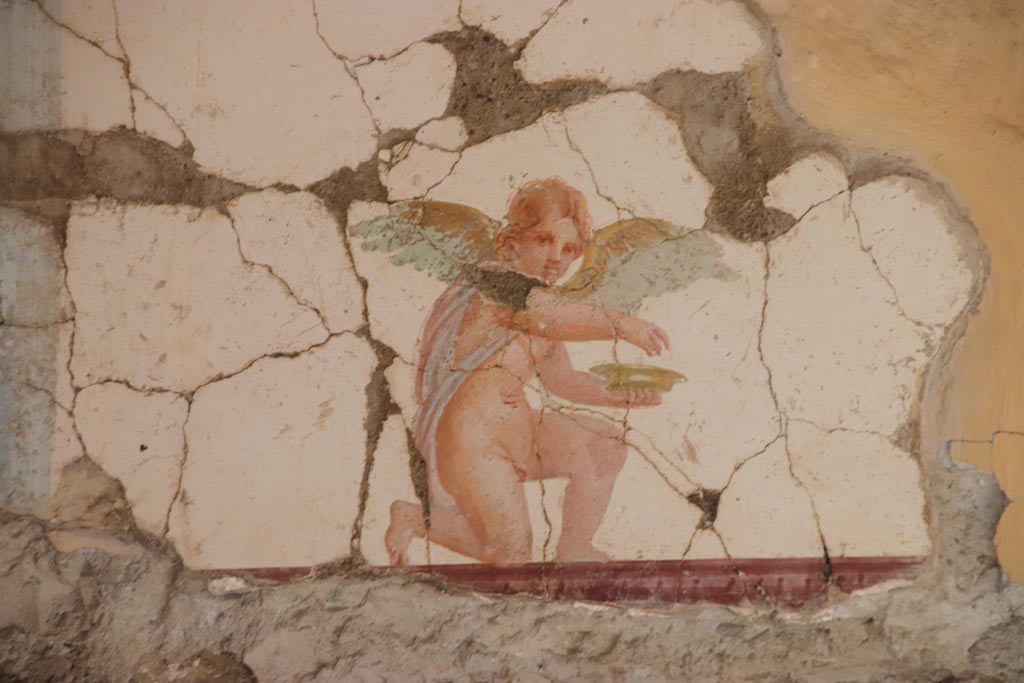 Villa San Marco, Stabiae, October 2022.  
Room 30, painting of kneeling Eros holding a dish, from east wall above doorway to room 50, in north-east corner.  
Photo courtesy of Klaus Heese.