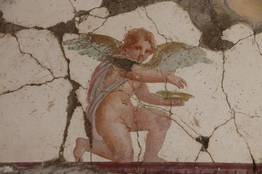 Villa San Marco, Stabiae, October 2022.  
Room 30, detail of kneeling Eros holding a dish, from east wall above doorway to room 50, in north-east corner.  
Photo courtesy of Klaus Heese.