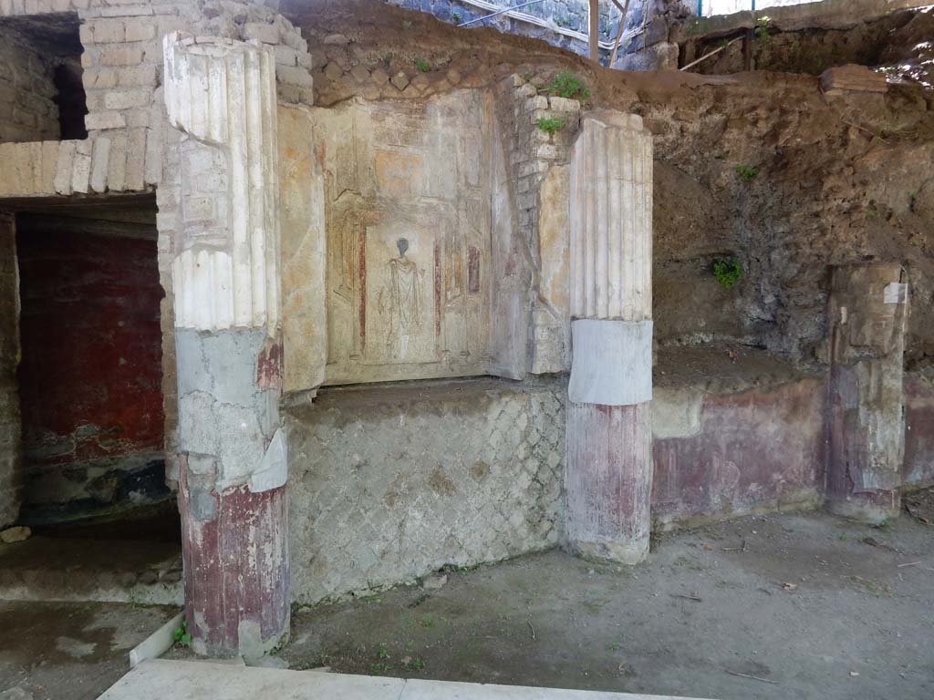 Villa San Marco, Stabiae, June 2019. Area 64, at south-east end of garden. Photo courtesy of Buzz Ferebee
According to the information card –
“On the south end of the large portico with swimming pool was a curving wall (nymphaeum) subdivided into eight exhedrae plastered with polychrome stuccoes, architectural motives and animated views, acting as a sort of stage-front for the swimming pool.
The central niches contained mosaics representing The Rape of Europe and Frixus with Elle.
Immediately behind the nymphaeum runs a tunnel (numbered 62-63), only partly excavated, with the same curvature as the nymphaeum.”