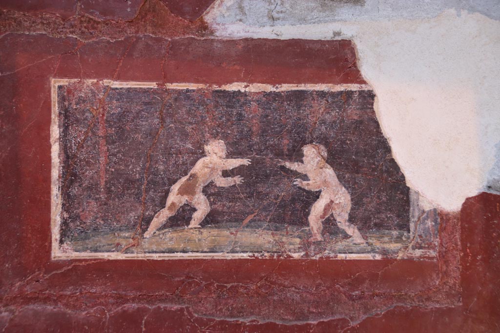Villa San Marco, Stabiae, October 2022. 
Room 25, detail of painted panel of two cupids wrestling, from east end of north wall. Photo courtesy of Klaus Heese.
(Note: in the photo above this (September 2019), this panel had not been re-inserted into the wall yet).