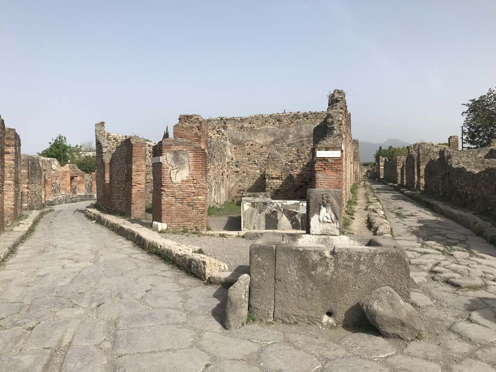 Via Consolare, on left, Pompeii. April 2019. 
Looking north towards fountain at junction with Via Consolare and Vicolo di Modesto, on right.
Photo courtesy of Rick Bauer.