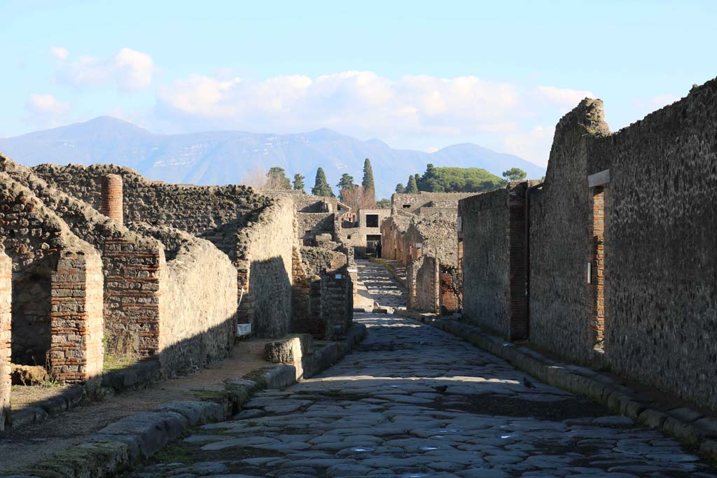 Via del Tempio d’Iside, Pompeii. December 2018. 
Looking east between VIII.4, on left, and VIII.7, on right, towards junction with Via Stabiana, and across into Vicolo del Menander. 
Photo courtesy of Aude Durand.