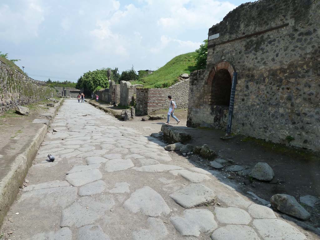 Via dell’Abbondanza, south side. May 2010. 
Looking east from near the end of II.4 towards the junction with Vicolo dell’Anfiteatro, on the right.
According to Garcia y Garcia, two bombs fell on the north-east corner of this insula on 19th September 1943.
This damaged the perimeter wall on the Via dell’Abbondanza and the niche, which was then restored.
See Garcia y Garcia, L., 2006. Danni di guerra a Pompei. Rome: L’Erma di Bretschneider. (p.45-6).