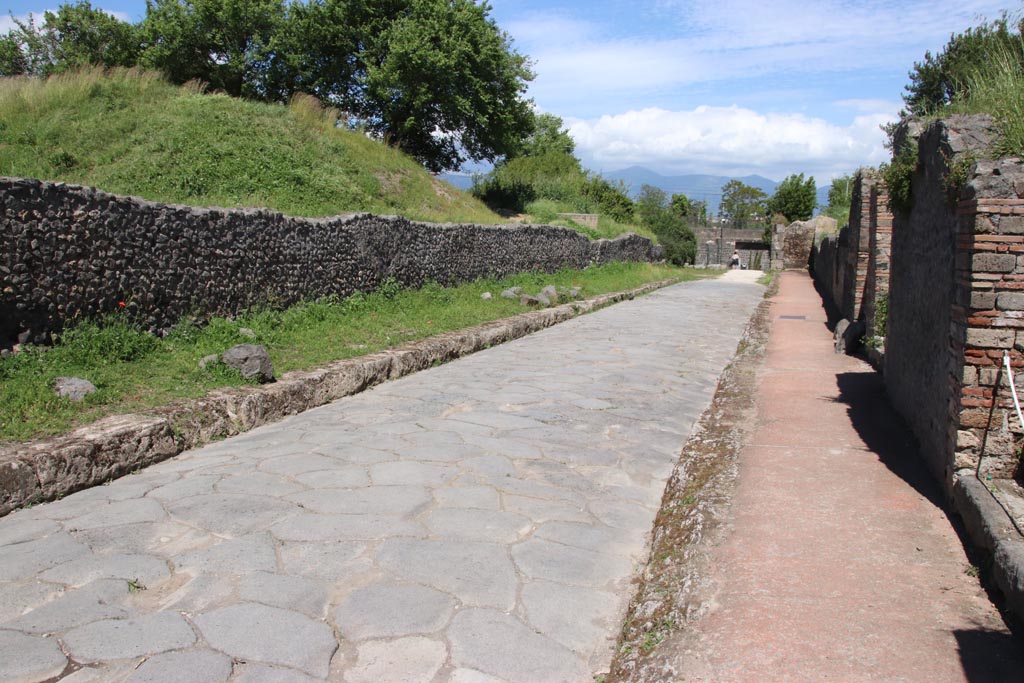 Via dell’Abbondanza between III.7 and II.5, Pompeii. May 2024. 
Looking east towards Porta di Sarno or Sarnus Gate. Photo courtesy of Klaus Heese.