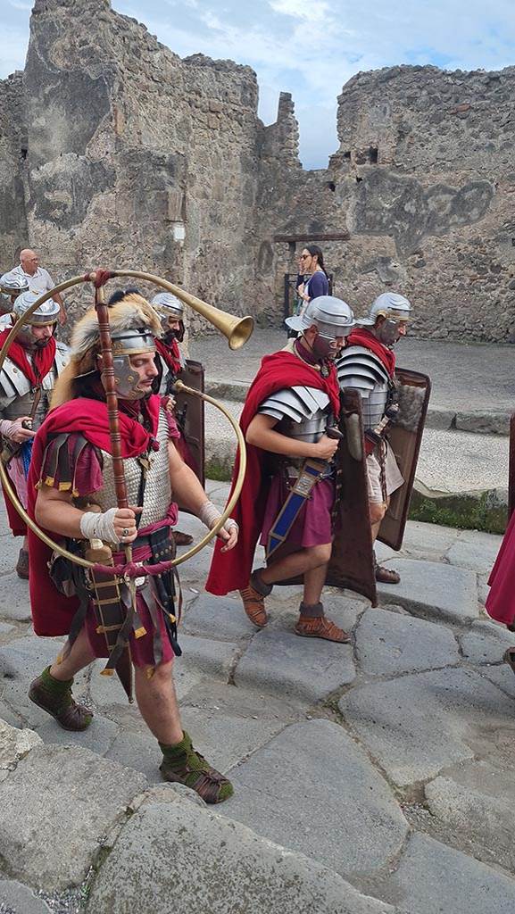 Via dell’Abbondanza, south side, at I.4.17. 28th September 2024. 
Soldiers marching including “Cornicen” with instrument used to signal orders to Legions.
“Ludi Pompeiani” event.  Photo courtesy of Giuseppe Ciaramella.

