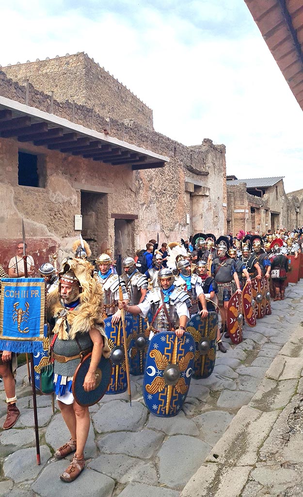 Via dell’Abbondanza, south side. 28th September 2024. 
Legionaries bearing the standard of the Cohors III Praetoria (3rd Cohort of the Praetorian Guard).
Looking south-west towards I.7.3, on left, during “Ludi Pompeiani” event. 
Photo courtesy of Giuseppe Ciaramella.