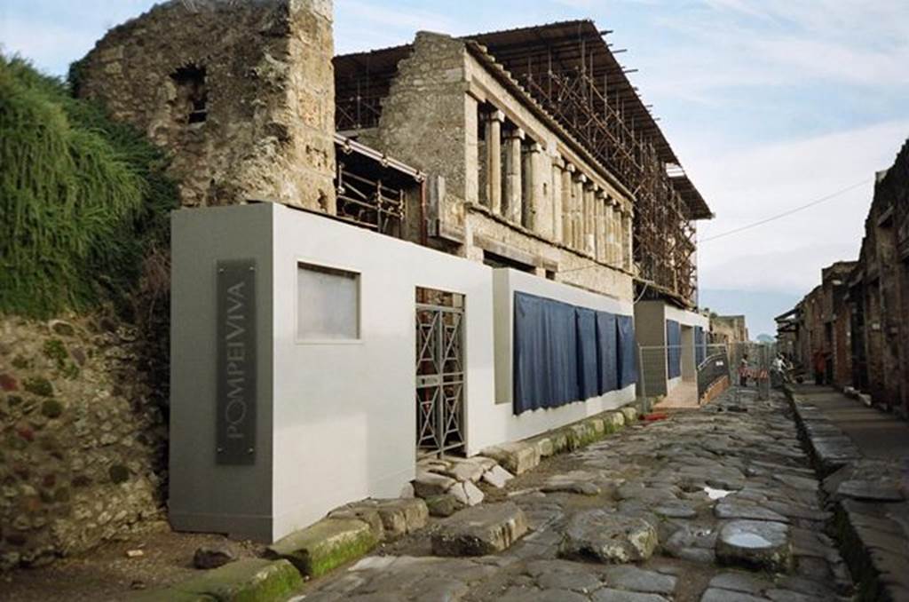 Via dell’ Abbondanza. North side. Looking east towards IX.11.8 (behind Pompeiviva sign), unnamed vicolo (behind the gate) and IX.12. November 2009.  Photo courtesy of Rick Bauer