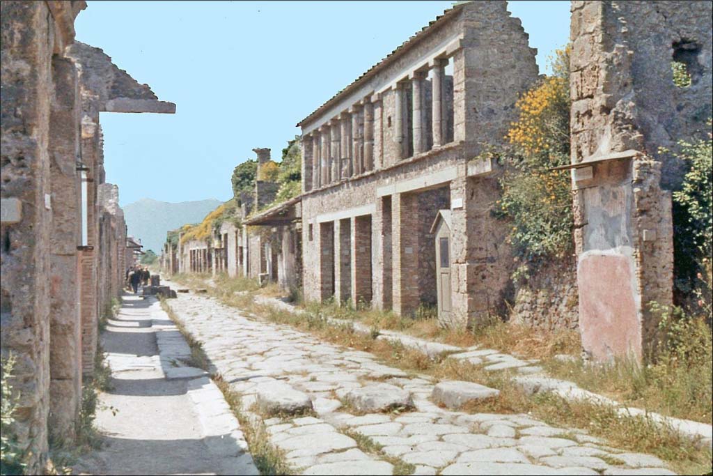 Via dell’Abbondanza, Pompeii. June 1962. Looking east between IX.12 and 1.8, from near IX.11.8, on left
Photo by Brian Philp: Pictorial Colour Slides, forwarded by Peter Woods
(P43.14 POMPEII House facades along a principal street)