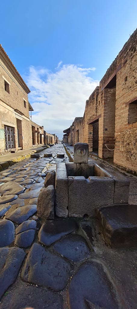 Via dell’Abbondanza, Pompeii. April 2022.
Looking east to fountain in roadway between IX.13 and I.9. 
Photo courtesy of Giuseppe Ciaramella.