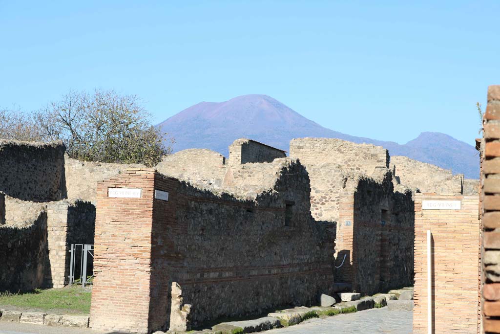 Via dell’Abbondanza, north side at VII.14.14, Pompeii, on left. December 2018. 
Looking north-west at junction with Vicolo del Lupanare, with Vesuvius towering above. Photo courtesy of Aude Durand.