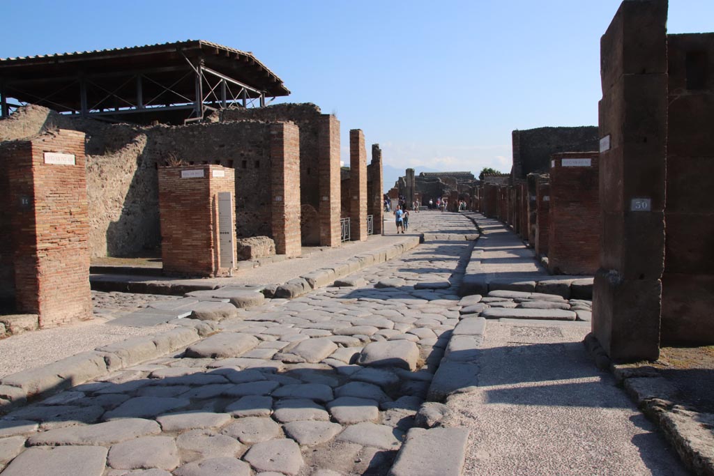 Via dell’Abbondanza, Pompeii. October 2022. 
Looking east towards junction with Vicolo del Lupanare, on left and Via dei Teatri, on right. Photo courtesy of Klaus Heese.