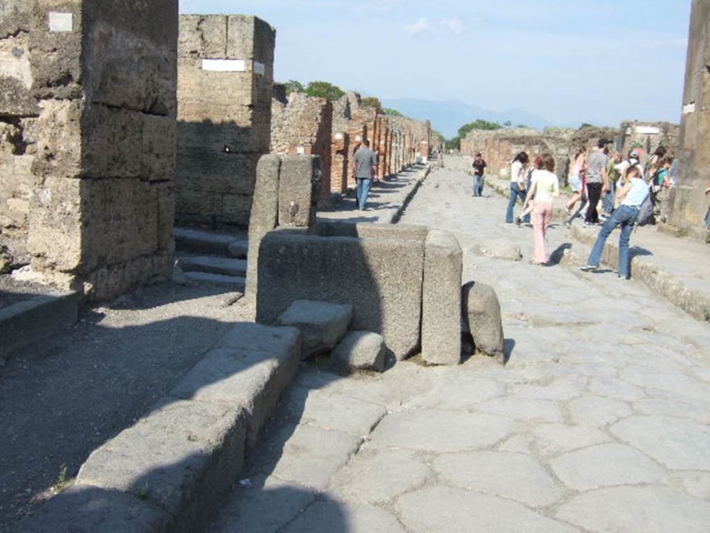 Via della Fortuna between VI.13 and VII.4. Looking east with Vicolo dei Vettii on left behind fountain.  The crowd on the right is going into Vicolo Storto. May 2006.